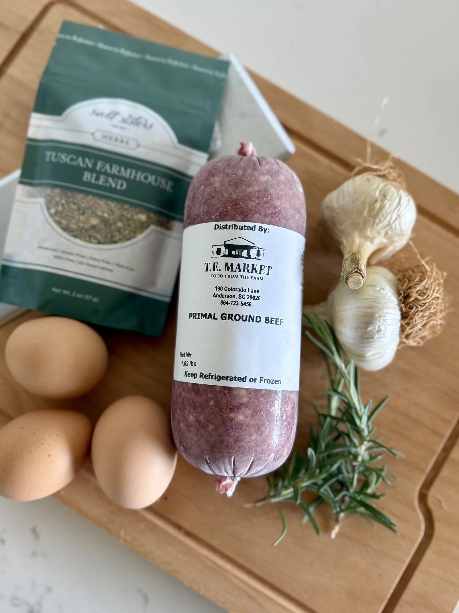 Primal Blend ground beef on a cutting board with eggs and herbs